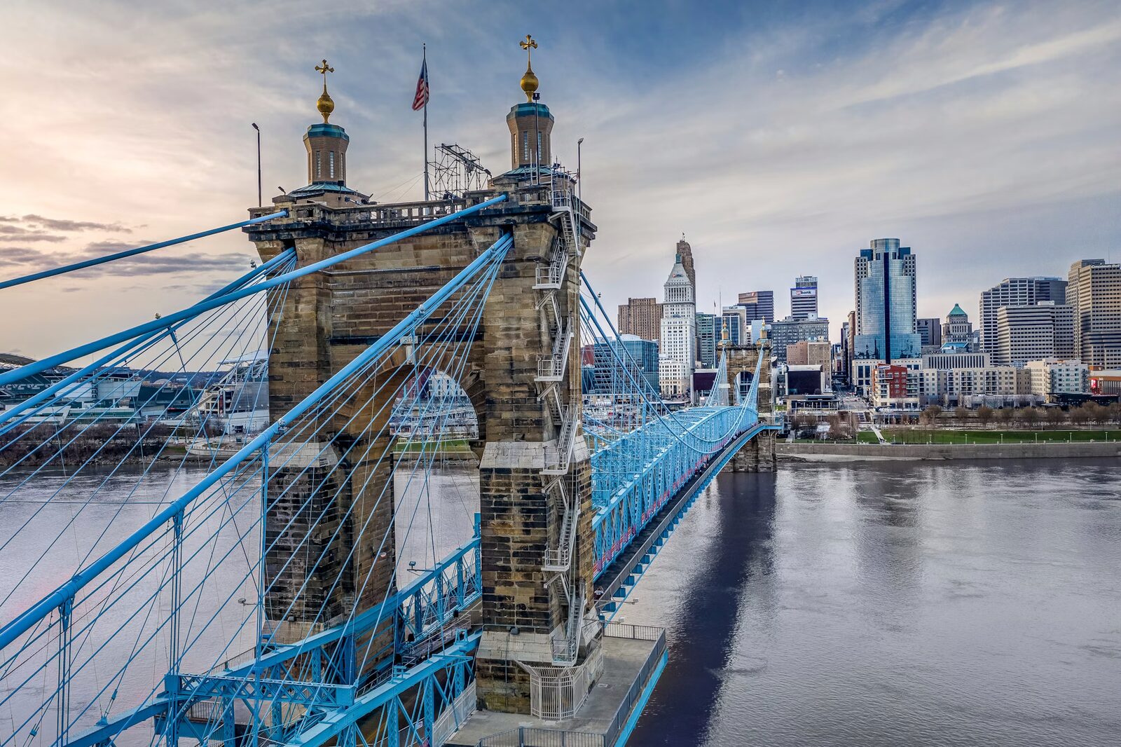 The John A. Roebling Suspension Bridge over the Ohio River with the Cincinnati skyline at dusk